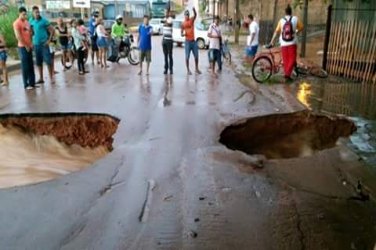 Córrego transborda e abre cratera em rua na capital